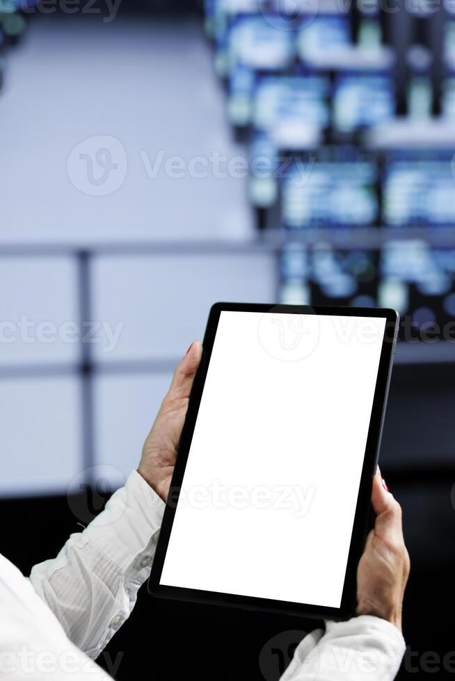 Close up shot of mock up tablet used by experienced serviceman in data center using server cabinets to deliver massive computing power, control network resources, process and store datasets photo