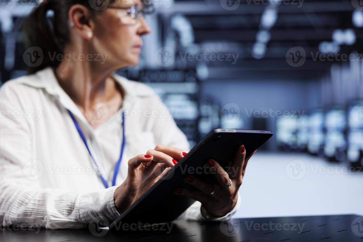 Trained serviceman using tablet to assess server security blips arising due to unsecured network connections. Qualified repairman ensuring data center is impenetrable by malware attacks photo