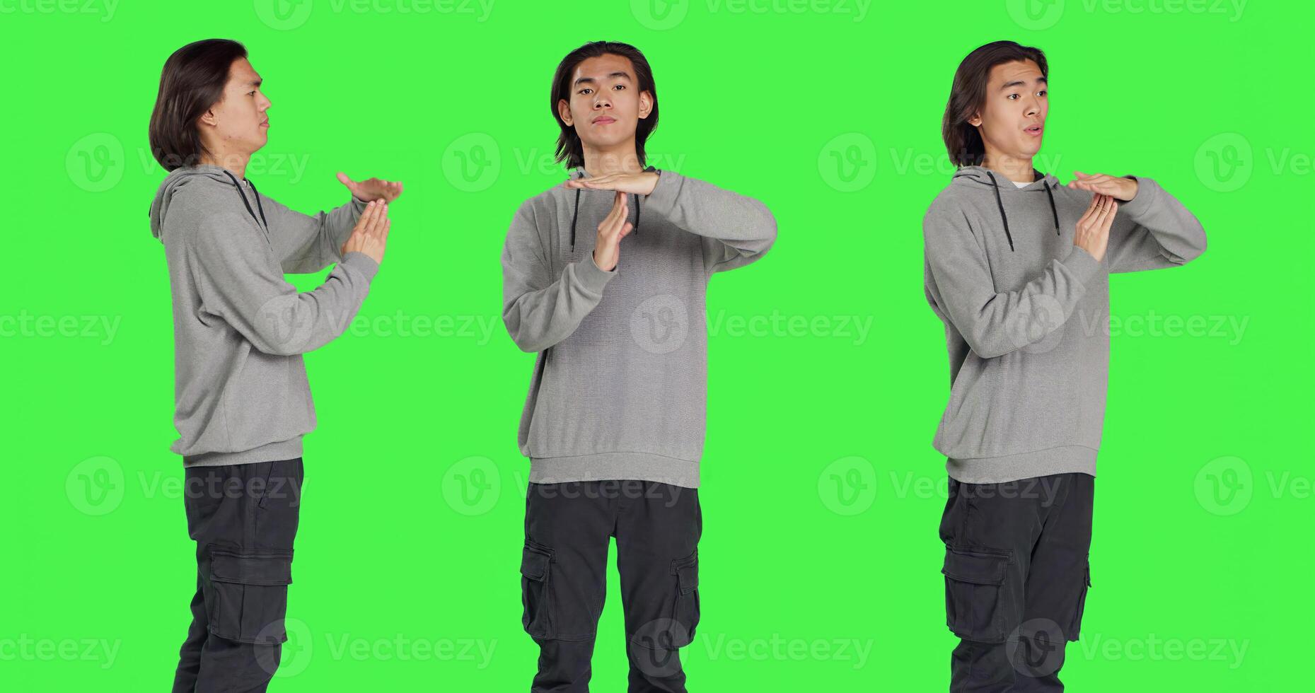 Person does timeout gesture with hands, asking for a break or pause against greenscreen in studio. Asian man showing disapproval and negative emotions on camera, stop gesture. photo