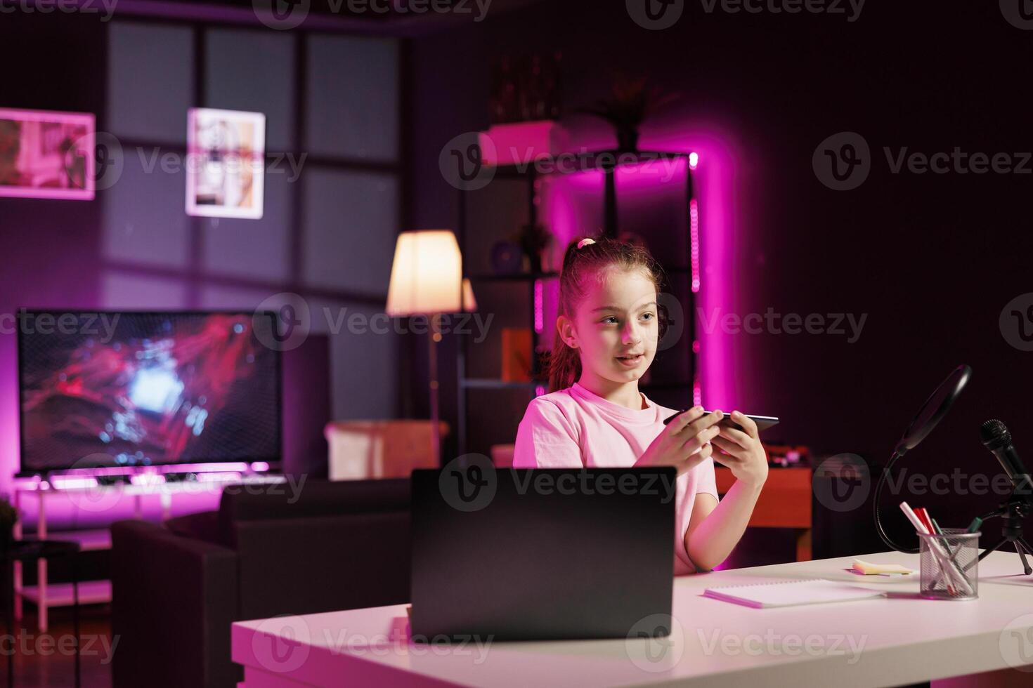 Child media star filming about best smartphones launched this year. Cute girl tech content creator recording mobile phone review, assessing build quality and performance photo