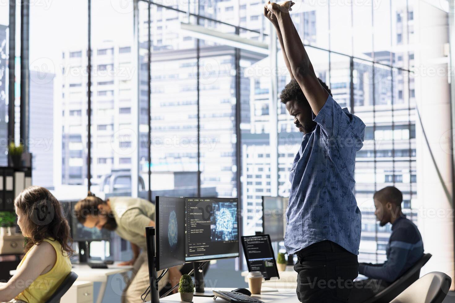 Tired admin stretching limbs while using computer for artificial intelligence computing simulating human brain. Fatigued employee relaxing back, feeling strained after working with AI neural networks photo