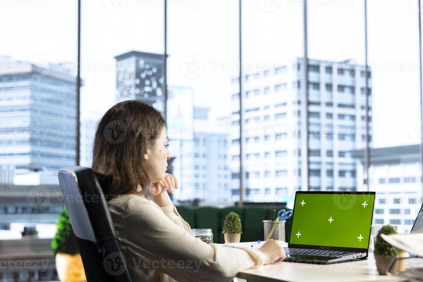 Woman company leader looking at isolated chroma key display in high end urban office, ambitious driven CEO with executive power. Businesswoman with strategic thinking in corporation. photo