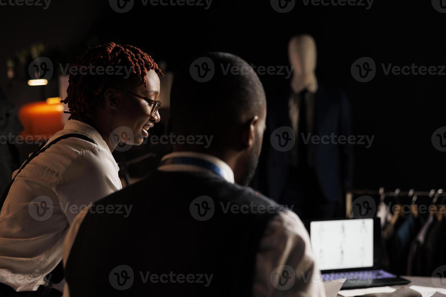 Happy african american coworkers in atelier shop designing exquisite sartorial menswear collection. Professional suitmakers teamworking in tailoring studio, manufacturing custom handmade attire photo