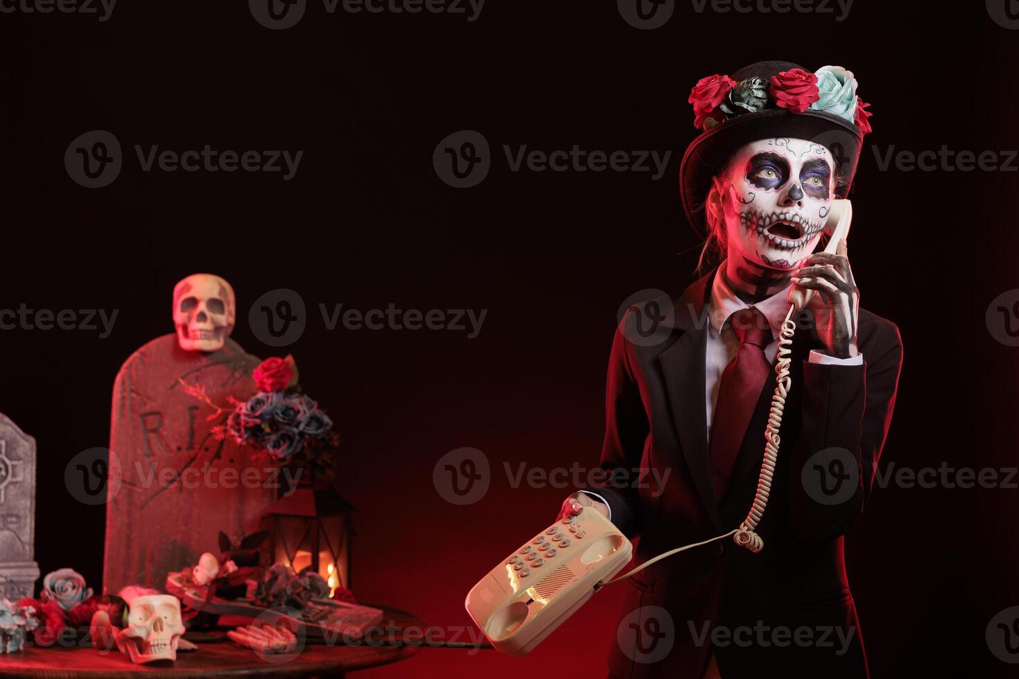 Lady talks on cord telephone at religious processions during Dia de los Muertos holiday. Woman uses landline phone to answer call,, wearing skeleton makeup symbolizing reverence for deceased photo
