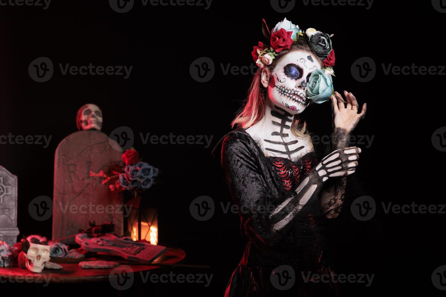 Woman holding blue rose, doing indigenous rites of honoring the dead during Dia de los Muerte. Lady with flower participating in Day of the Dead, Mexico annual event in honor of the deceased photo