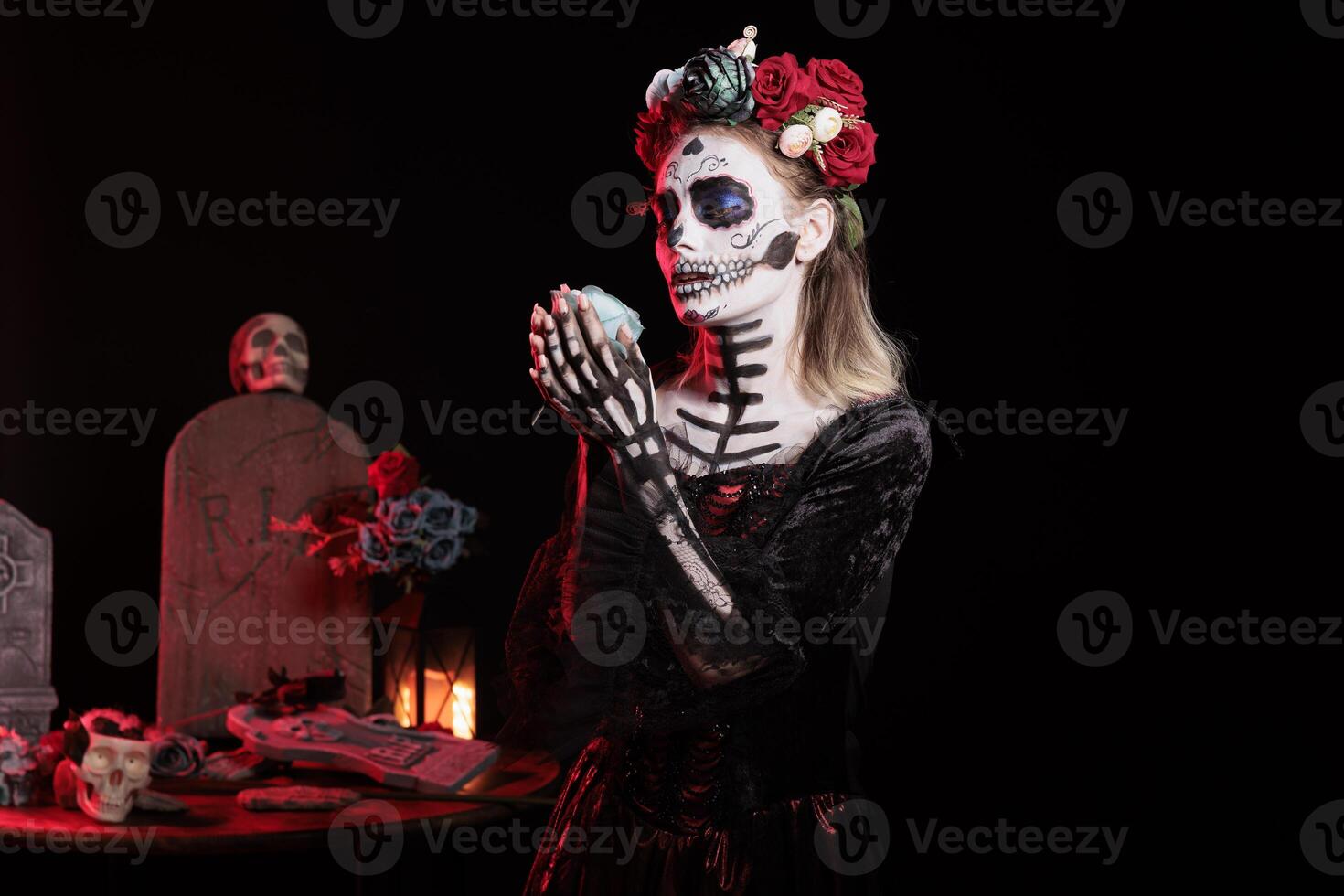 Woman enjoying nice rose scent during Day of the Dead Halloween event honoring dead loved ones. Scary lady smelling flower aroma during ancient Aztec custom of celebrating ancestors photo