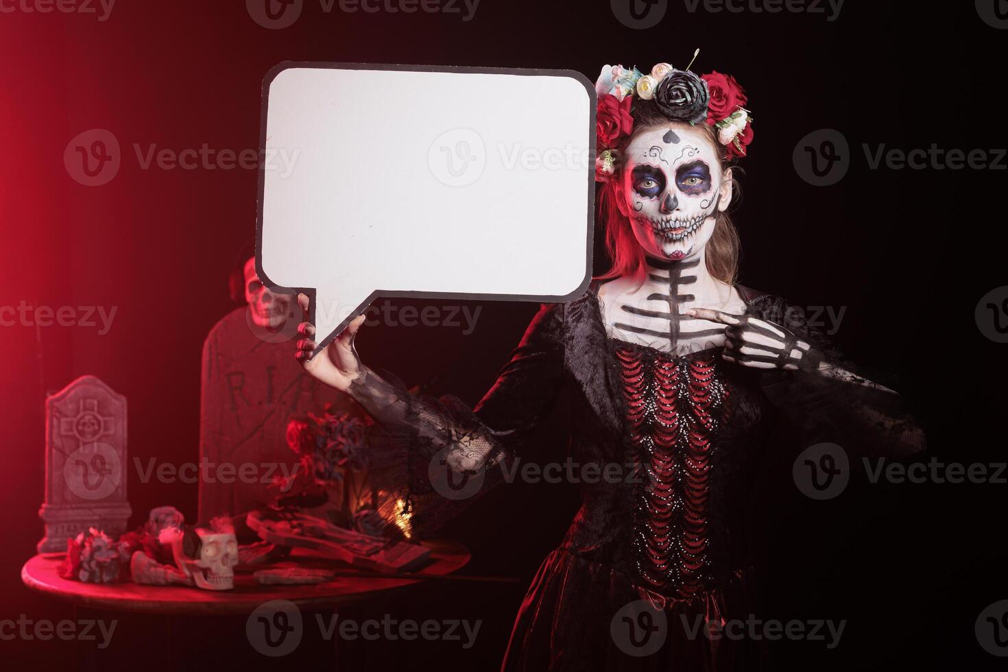 Portrait of woman dressed in Day of the Dead costume celebrating Dia de los Muertos, holding speech bubble. Girl wearing skeleton makeup using isolated copyspace template, promoting Mexican culture photo