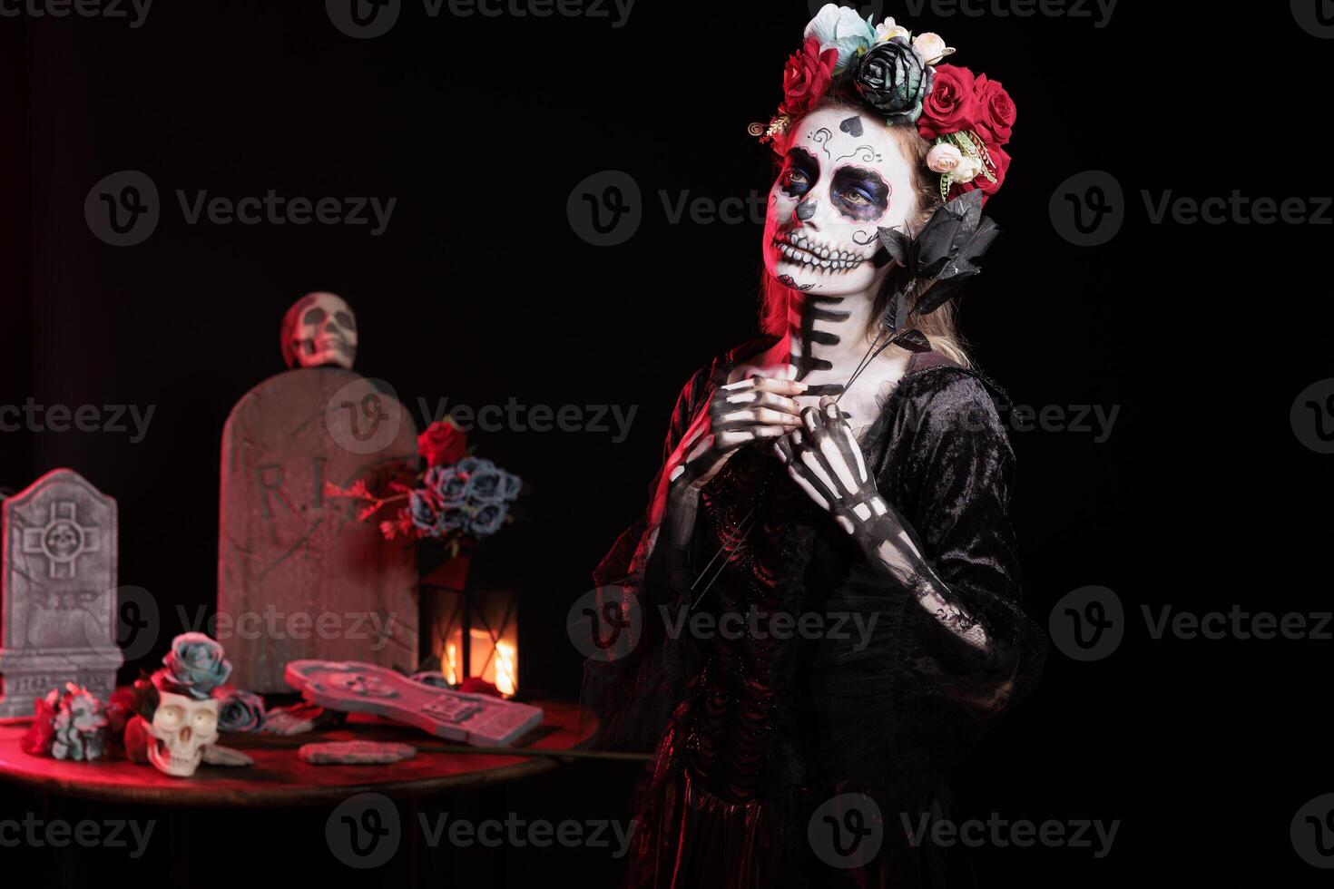 Woman holding black rose participating at Dia de los Muertos party, preserving cultural traditions between generations. Eerie lady with flower wearing la Catrina costume to celebrate Mexican culture photo