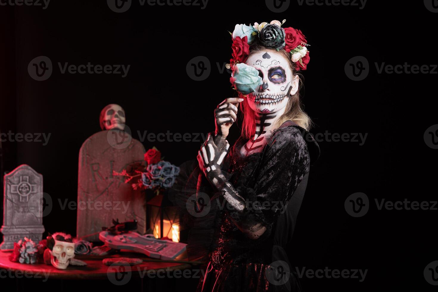 Woman doing sensual pose with blue rose, doing indigenous rites of honoring the dead during Dia de los Muerte. Seductive girl with flower participating in Day of the Dead in honor of the deceased photo