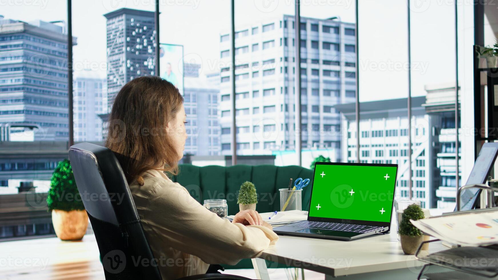 Woman company leader looking at isolated chroma key display in high end urban office, ambitious driven CEO with executive power. Businesswoman with strategic thinking in corporation. Camera A. photo