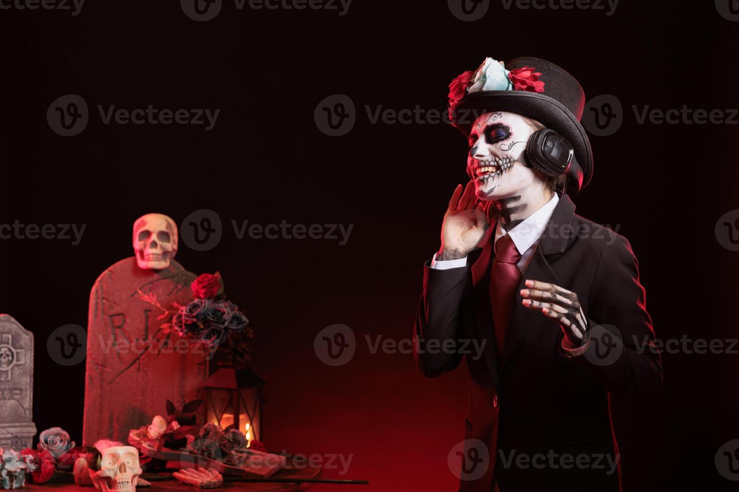Jolly woman dancing at Day of the Dead event to remember the deceased. Upbeat lady with headphones doing dance moves during Mexican holiday of remembrance for those who have passed photo