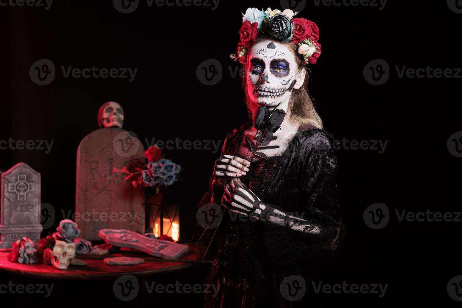 Woman dressed in Day of the Dead costume with flower wreath on head celebrating Dia de los Muertos. Girl wearing skeleton makeup promoting Mexican culture during Halloween, holding black roses photo