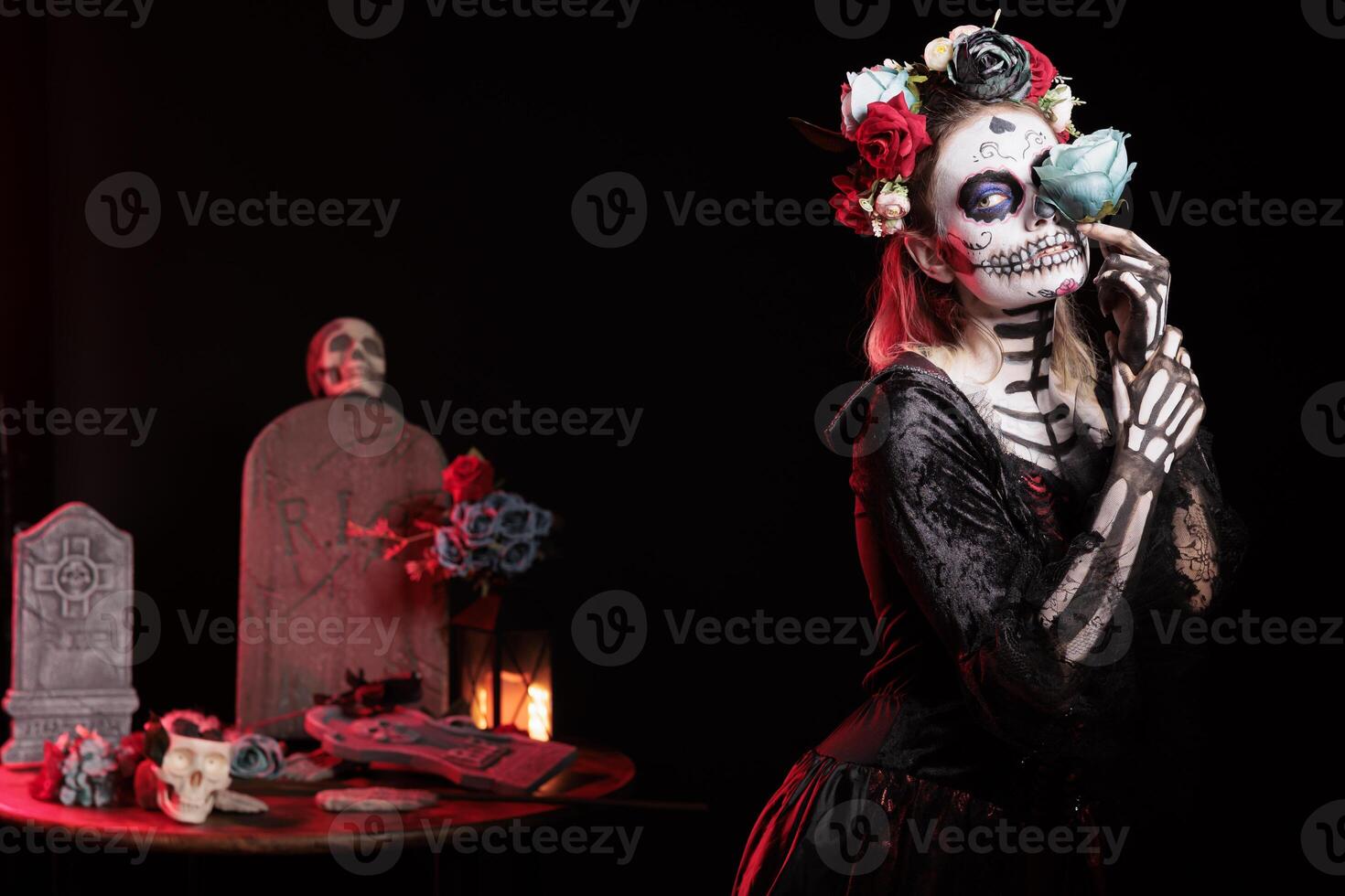 Haunting woman posing with blue rose during Dia de los Muertos celebration, preserving cultural tradition. Macabre lady portraying la Catrina character to celebrate Mexican culture photo