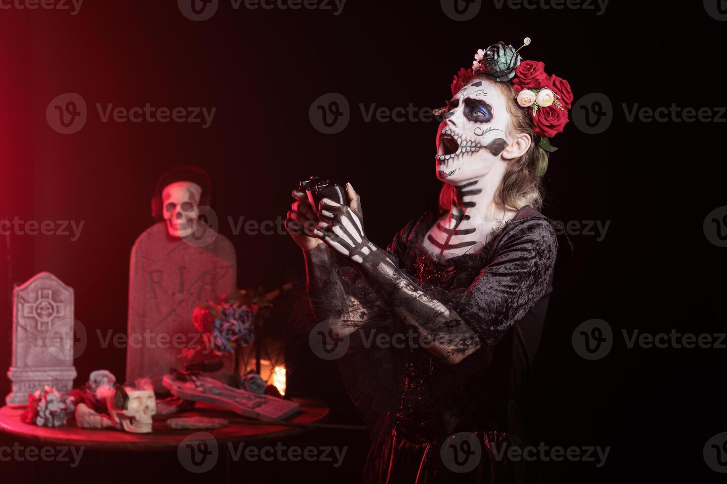 Woman raging after losing videogame during Day of the Dead. Mysterious lady holding controller, upset after being defeated, surrounded by frightening funeral items during Halloween horror event photo