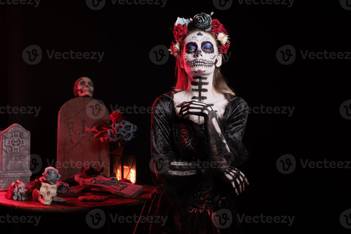 Portrait of woman during Day of the Dead Mexican event honoring dead loved ones, graveyard background. Scary lady with cadaver body paint during ancient Aztec custom of celebrating ancestors photo