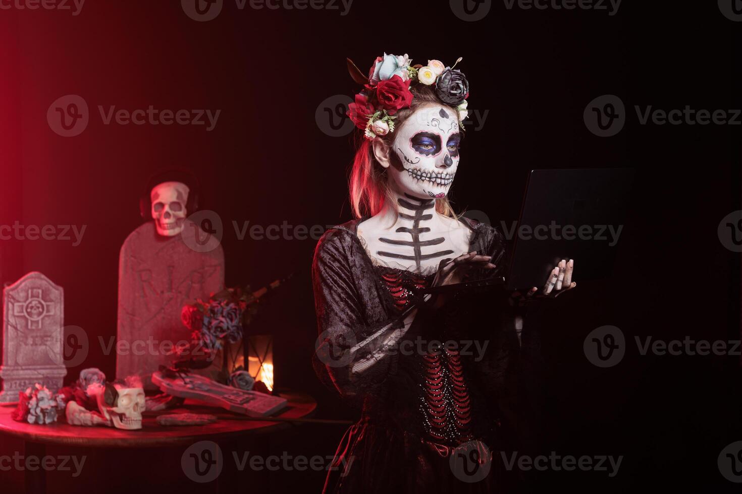 Woman sending emails on notebook at Day of the Dead event to remember the deceased. Lady working on laptop during Mexican holiday of remembrance for those who have passed photo