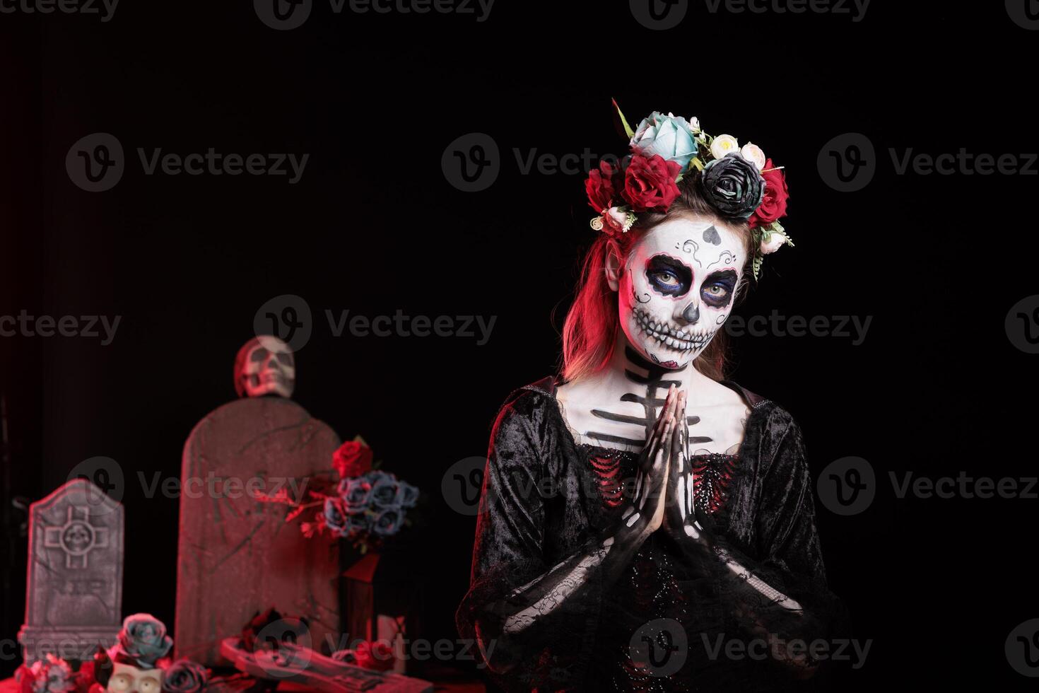 Woman doing praying hand gesture at Day of the Dead event to remember the deceased. Spiritual lady doing religious gesturing during Mexican holiday of remembrance for those who have passed photo