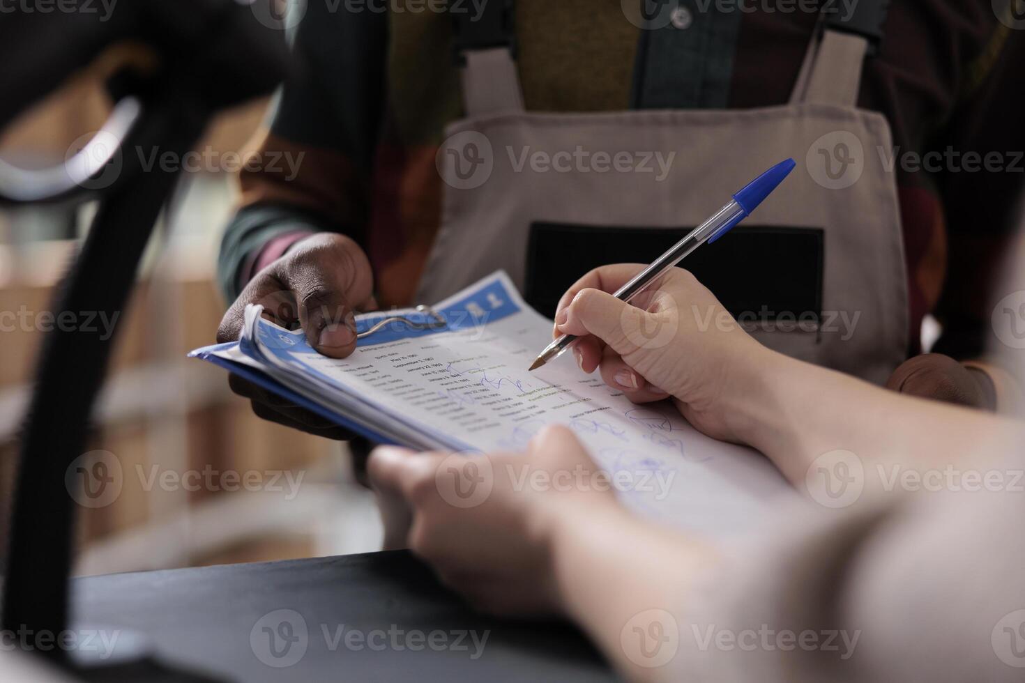 Storage room supervisor signing logistics report, discussing merchandise inventory working at goods quality control. Diverse team preparing customers orders for shipping in warehouse. Close up photo