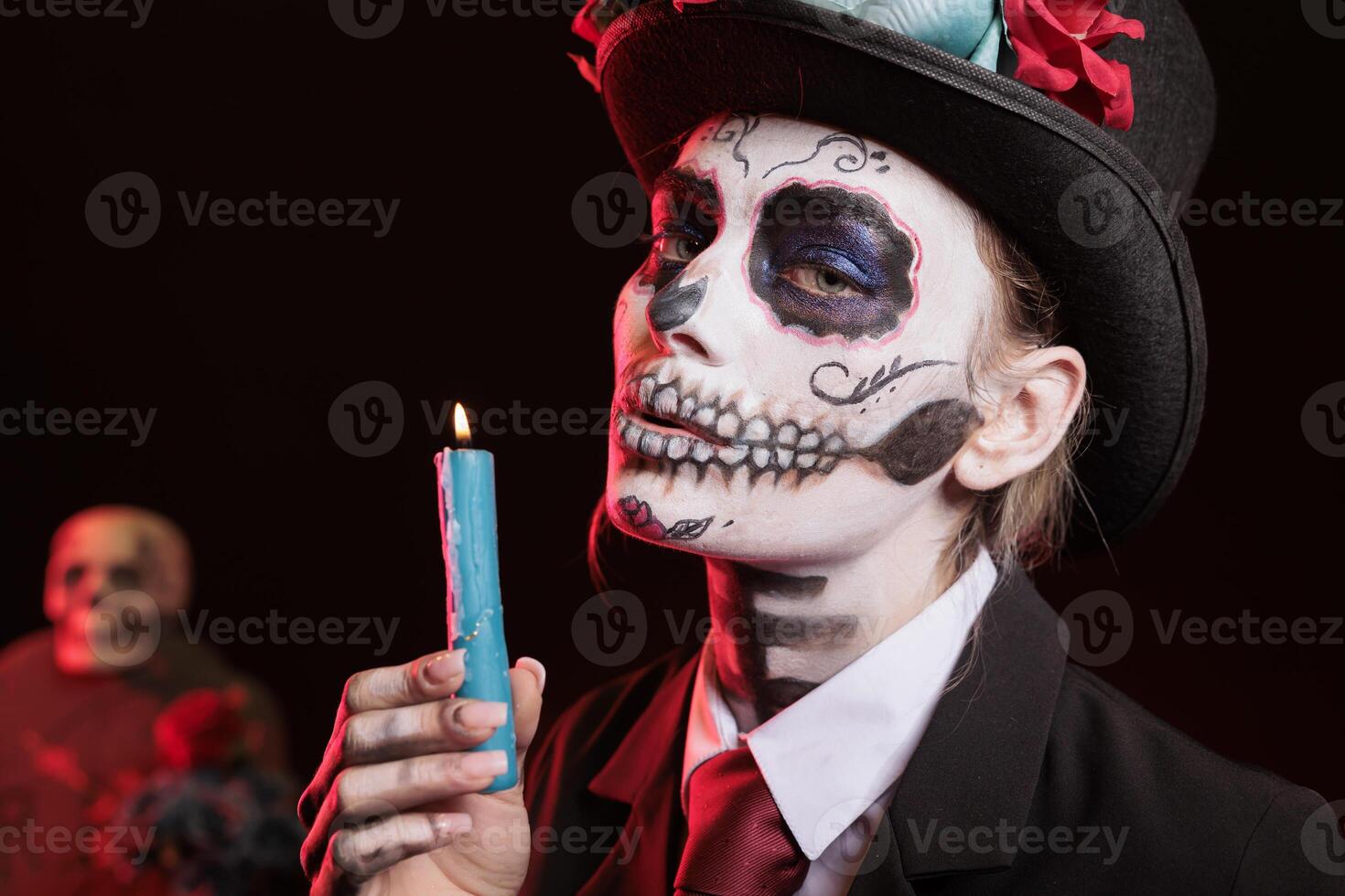 Lady lighting candle for magic ritual at religious processions during Dia de los Muertos november holiday. Woman with candlestick on fire, wearing skeleton makeup symbolizing reverence for deceased photo