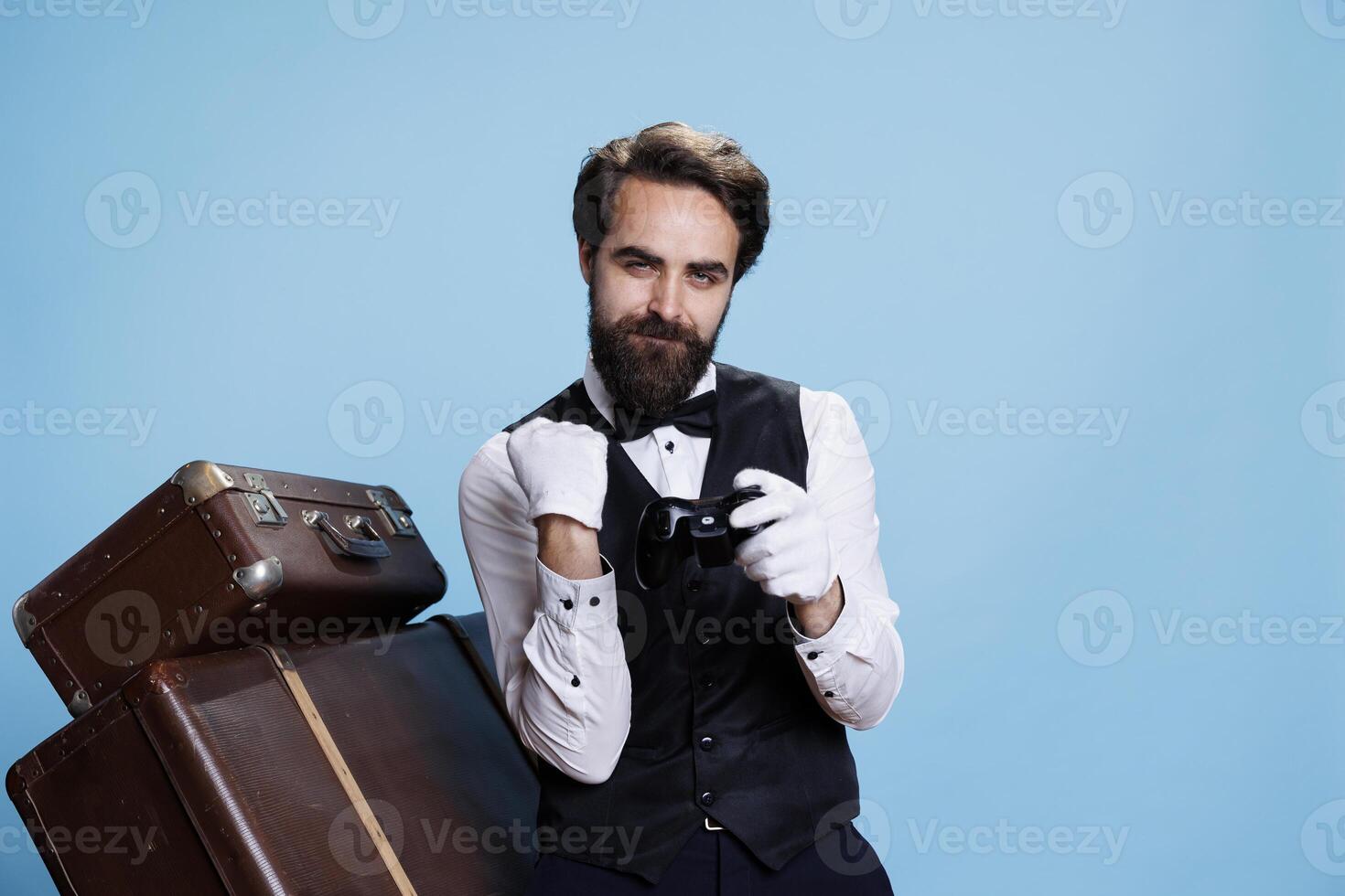 Hotel concierge wins gameplay on camera, gaming using remote controller and feeling cheerful about competition success. Confident gamer and bellboy plays online challenge. photo