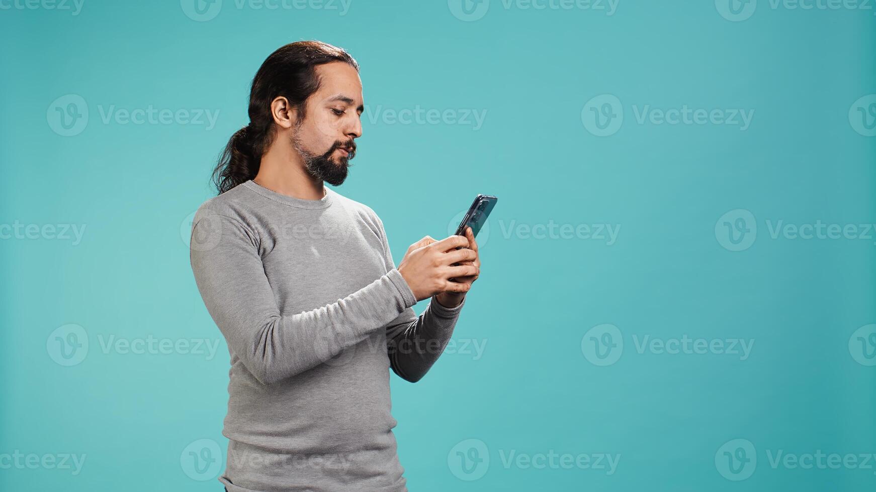 Smiling man having friendly conversation with friends during teleconference meeting using smartphone, studio background. Person having fun catching up with mates during online videocall, camera B photo