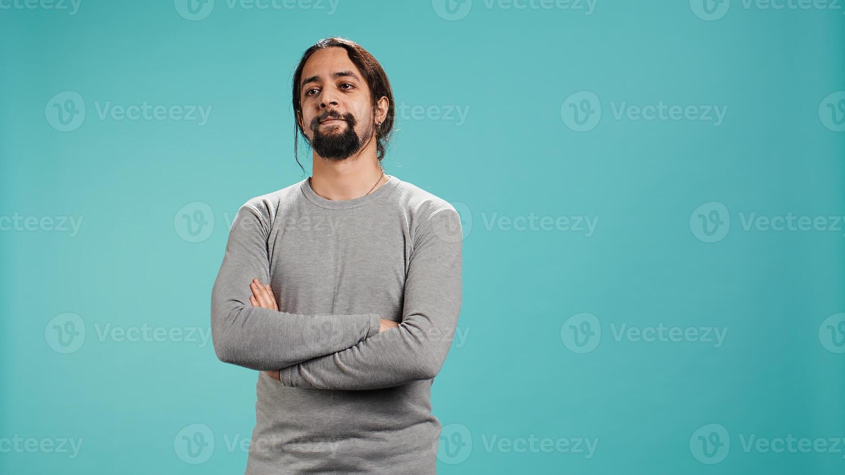 Portrait of cheerful Arab man smiling, looking pleased, isolated over blue studio background. Happy expressive person stylishly dressed grinning, feeling satisfied, camera B photo