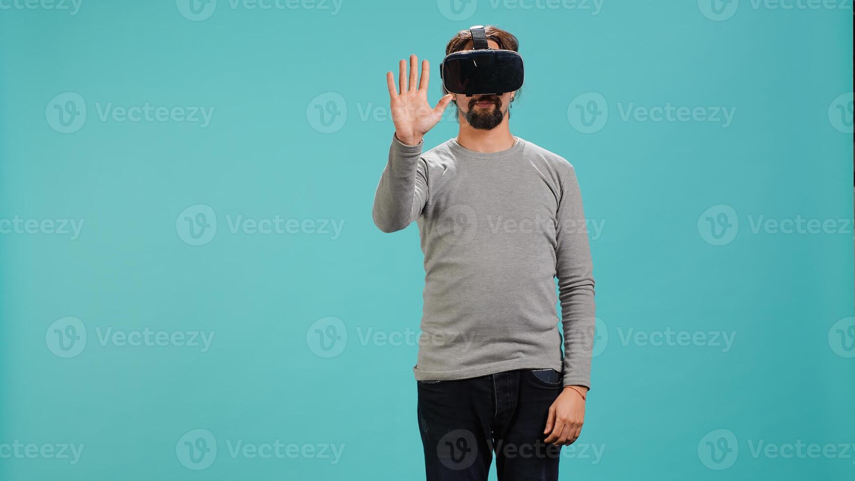 Tech enthusiast wearing virtual reality goggles, doing zooming in gestures. Arab man using high tech futuristic modern VR glasses, making tactile touching gesturing, studio background, camera A photo