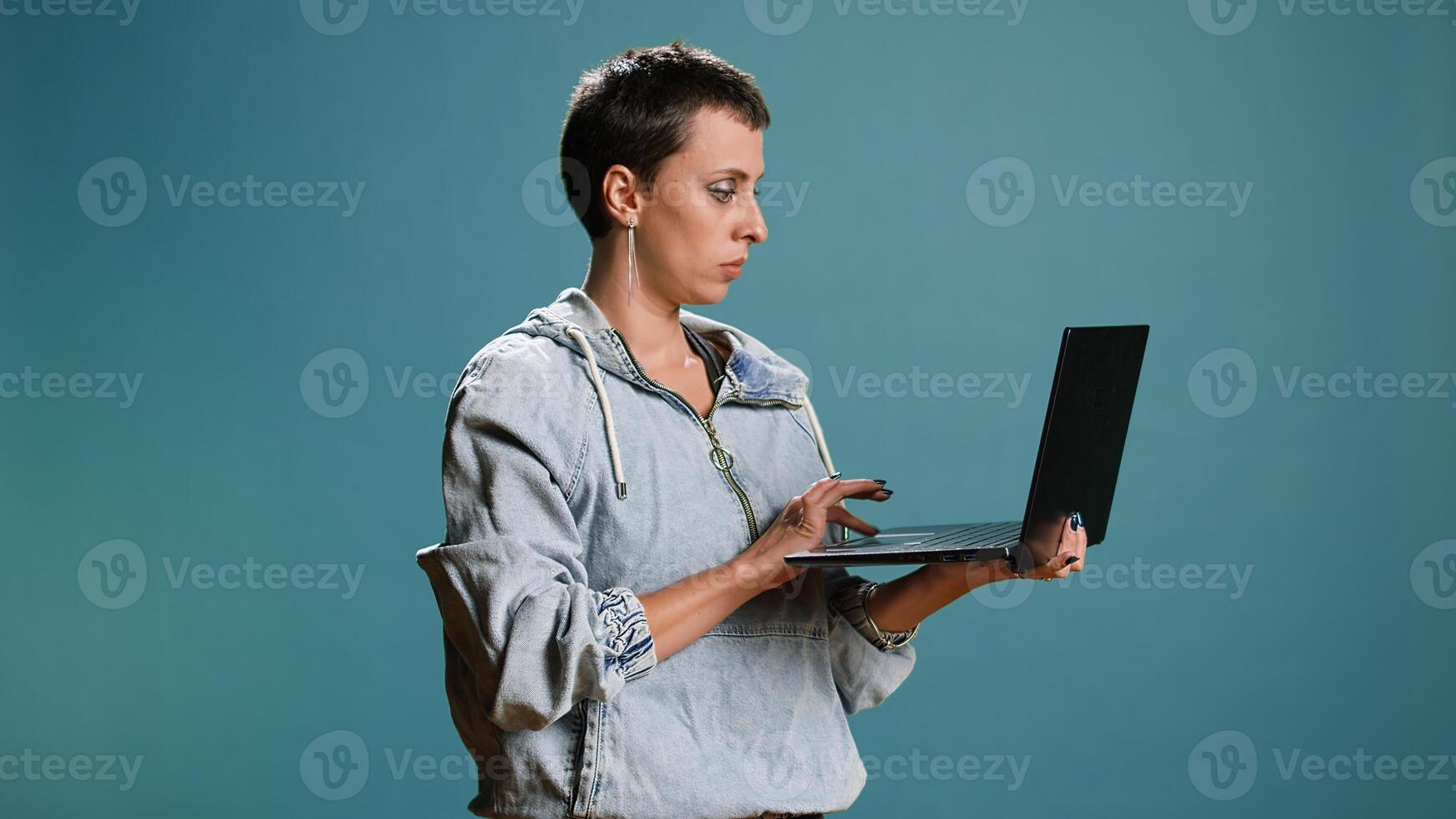 Casual woman browsing web on her laptop for freelance work in studio, remote network. Wireless computer user blogging on a new interface, trendy modern tech person. Camera A. photo