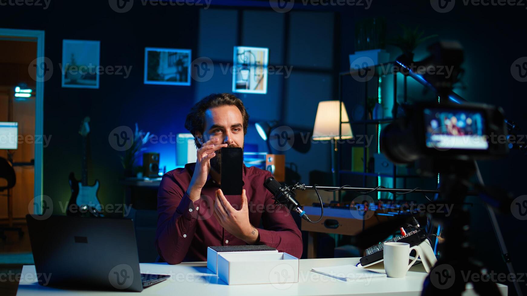 Tech guru assessing smartphone performance, feeling happy with high quality components used. Content creator shoots mobile phone review for online channel, recommending it, camera B photo