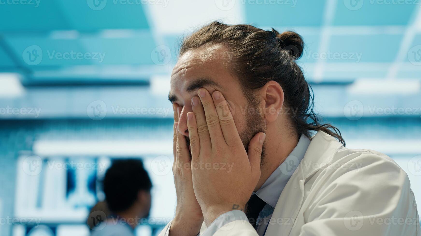 Worried doctor feeling tired and struggling with analytics for a diagnosis, overworked medic under pressure in private facility. Physician expert trying to provide treatment. Camera A. photo