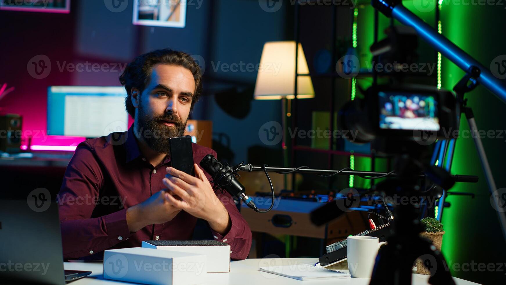 Tech guru using professional camera to film technology review of new cellphone, doing unboxing . Content creator showing phone box to subscribers, recording with high tech gear, camera A photo