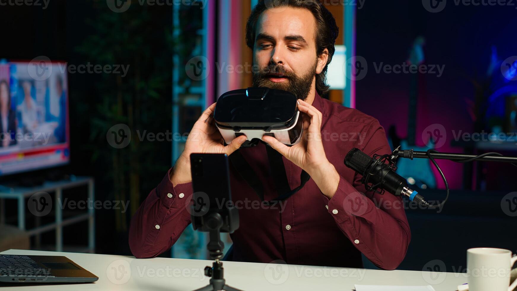 Media star in neon lit studio presents VR goggles from brand sponsoring , closely analyzing features. Influencer reviewing virtual reality headset for tech enthusiasts watching, camera A photo