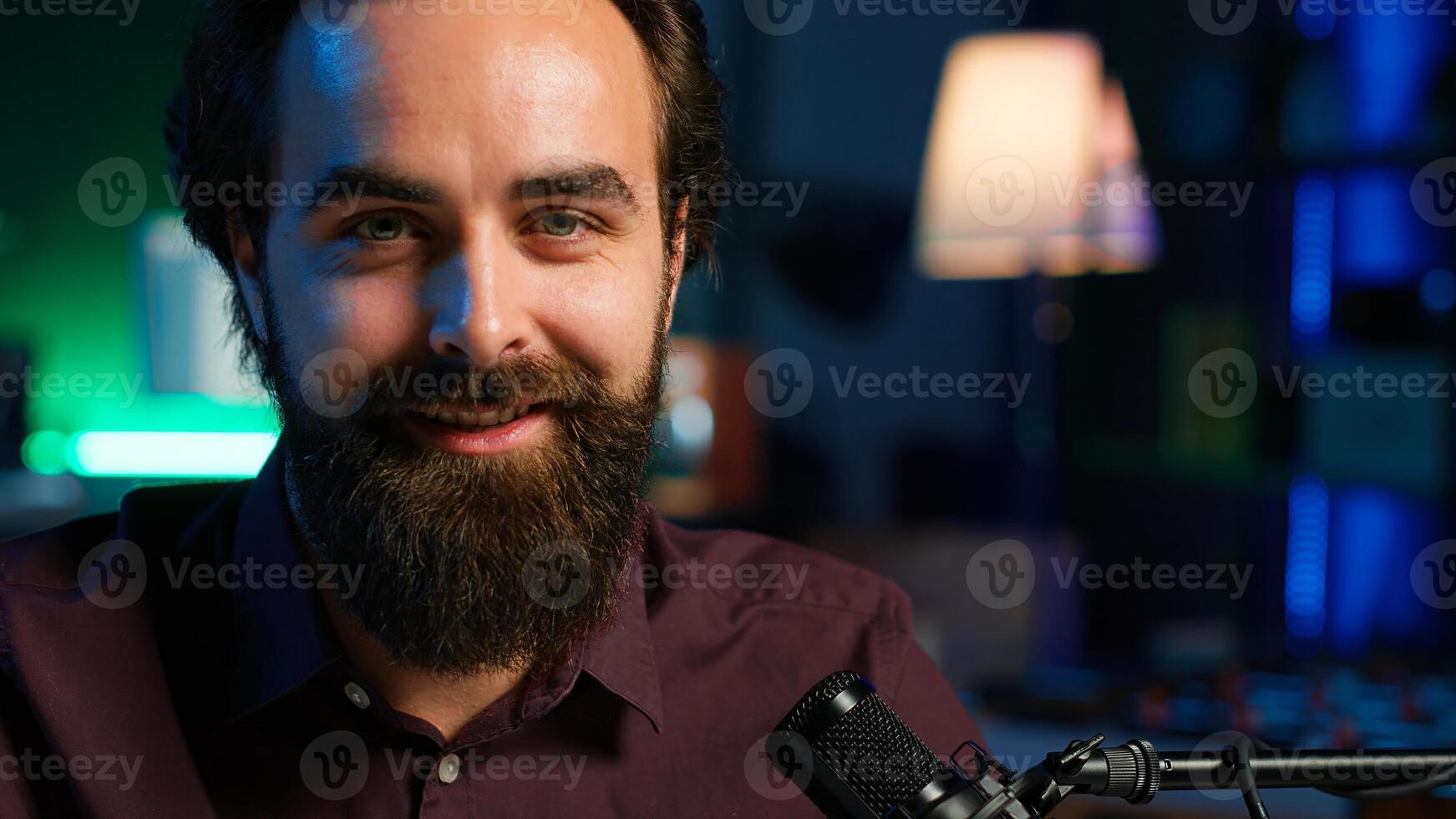 Portrait of content creator using high tech quality mic in studio to do ASMR , discussing with viewers. Smiling man using professional microphone to record podcast, camera A close up photo
