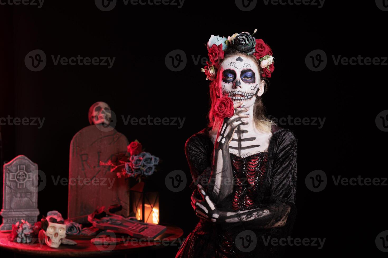 Lady with red rose at religious processions during Dia de los Muertos november holiday. Woman holding flower, wearing skeleton makeup symbolizing reverence for the deceased, studio background photo