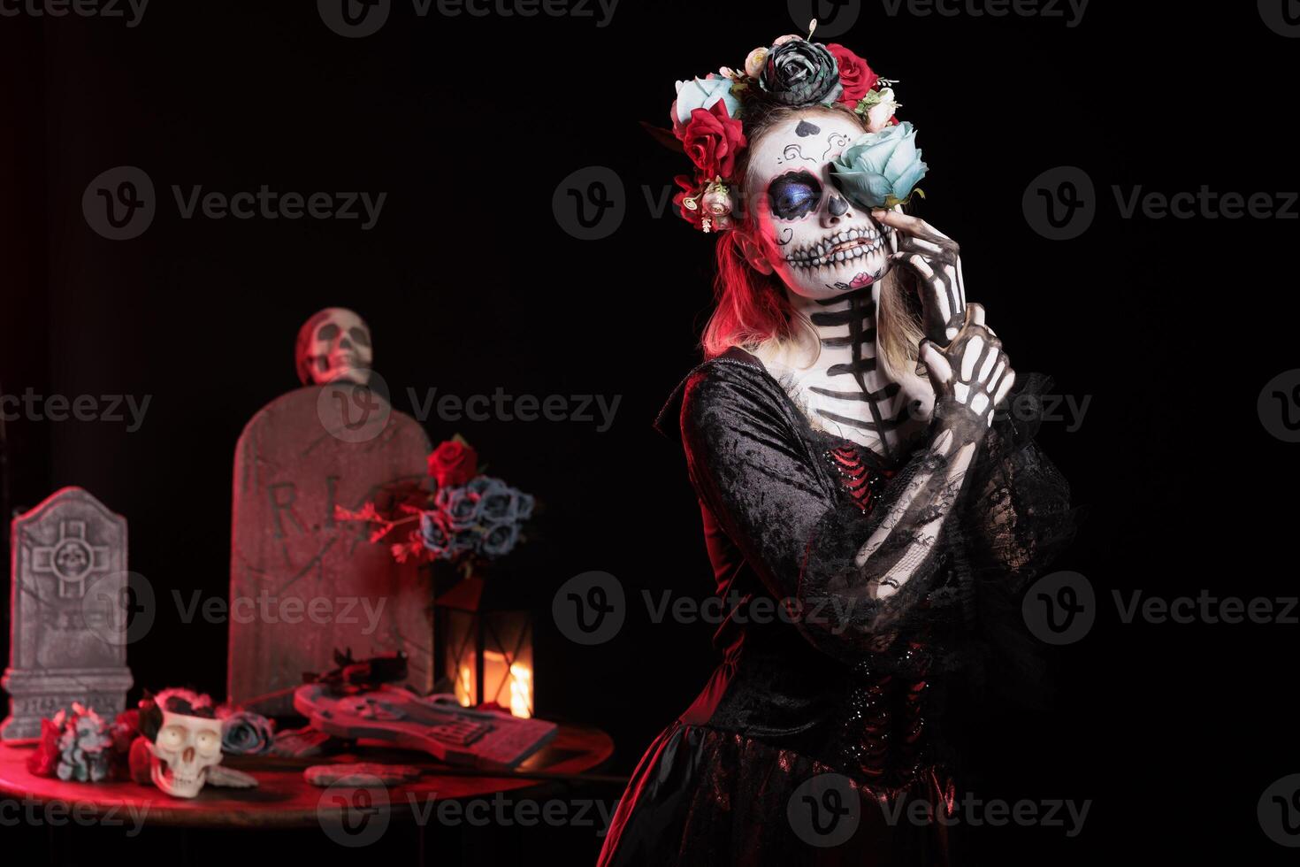 Girl doing mystic witchcraft at Dia de los Muertes indigenous rites of honoring the dead. Woman with rose wearing corpse body paint, participating at Day of the Dead in honor of the deceased photo