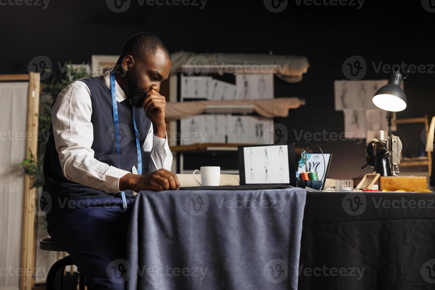 African american suitmaker overthinking in tailoring studio, working on custom made stylish business suit. Fashion designer struggling for ideas for upcoming runway show collection photo