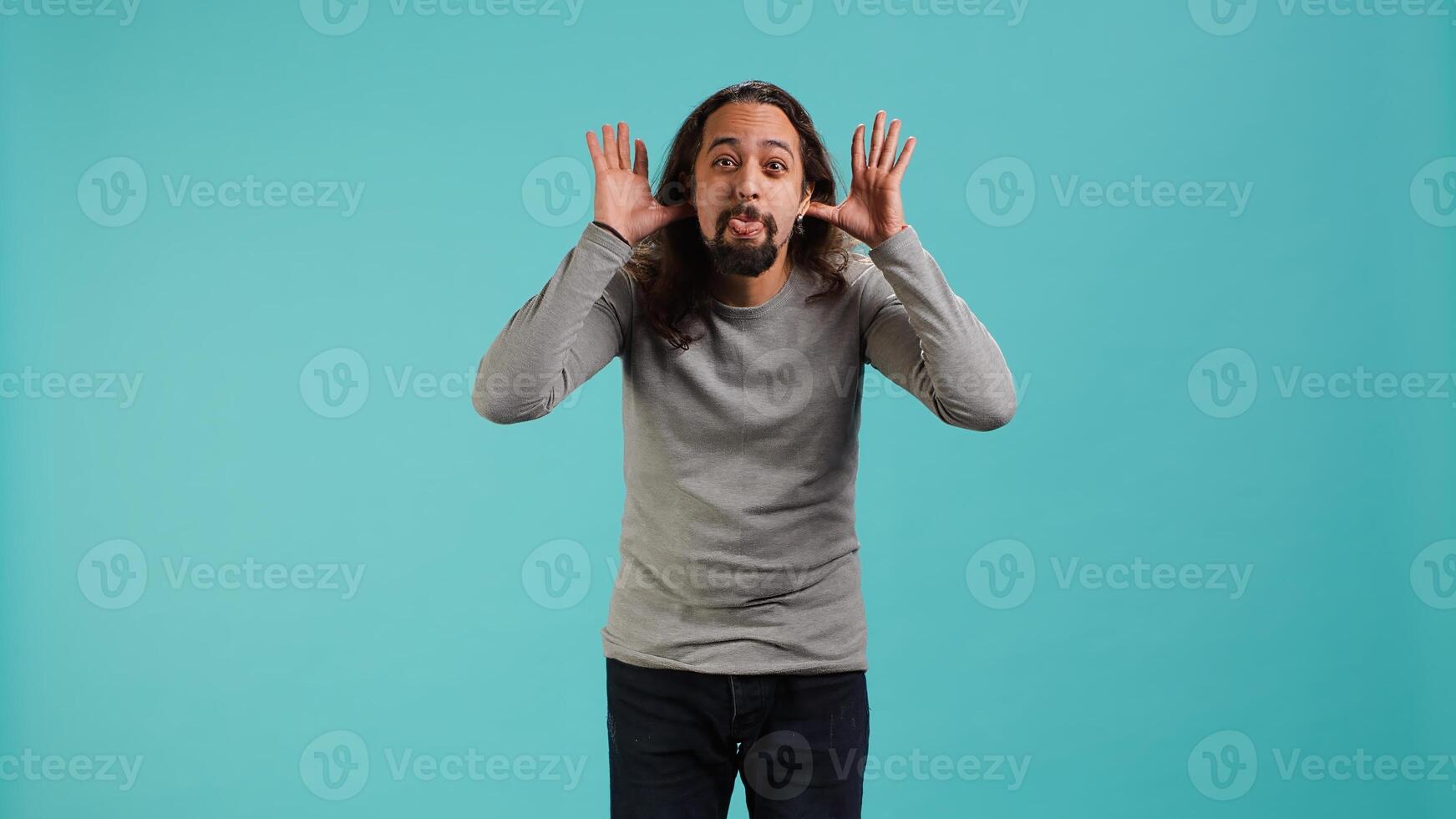 Portrait of spiteful man making exaggerated silly faces, mimicking someone, doing mocking gesturing. Person making goofy facial expressions, being playful, making fun, studio background, camera A photo