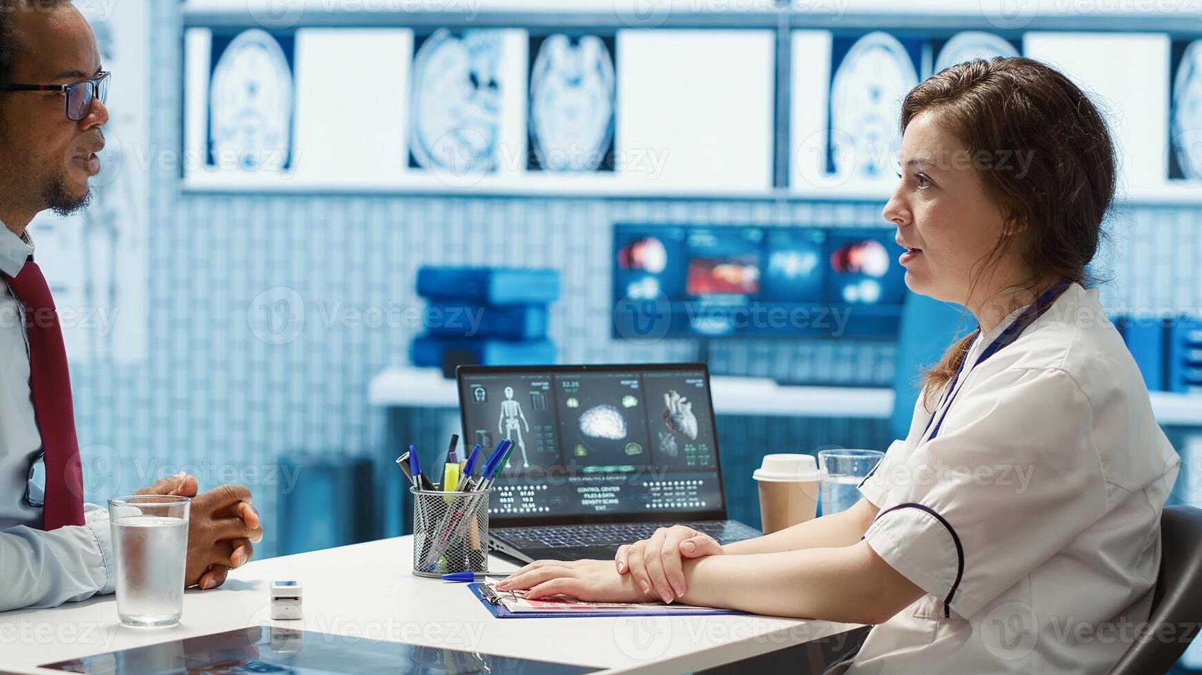 Physician meets with a patient to discuss medical results in a cabinet, using advanced diagnostic equipment to interpret x ray scans, demonstrating a professional healthcare approach. Camera A. photo