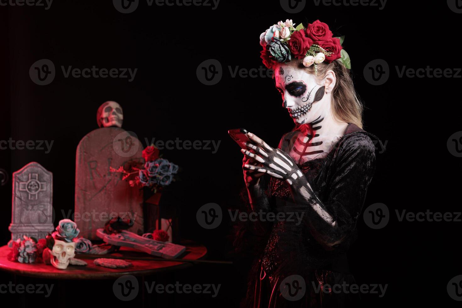 Girl texting friends on smartphone at Dia de los Muertes indigenous rites of honoring the dead. Woman checking social media on phone, participating at Day of the Dead in honor of the deceased photo