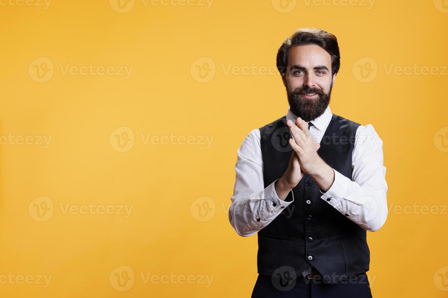 Positive butler applauding someone on camera, clapping hands to express congratulations for success. Happy waiter with suit and tie cheering for person in studio, boost confidence in friendly way. photo