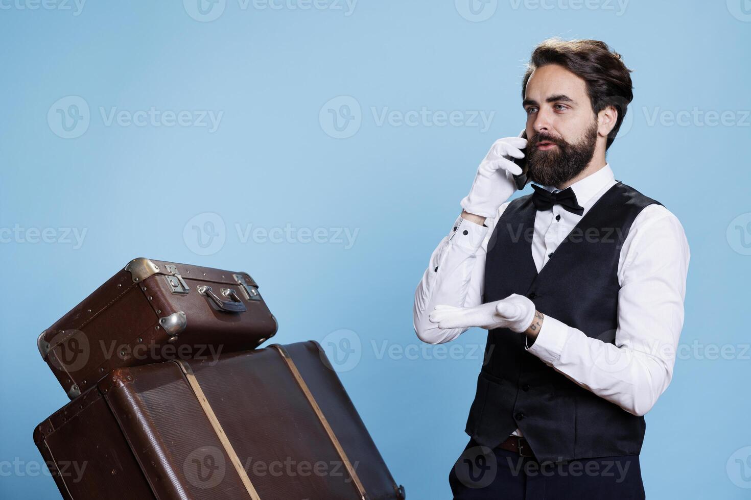 In a studio, hotel valet takes calls and handles bookings over the telephone. Competent and stylish doorman provides concierge services such as remote communication and requests. photo