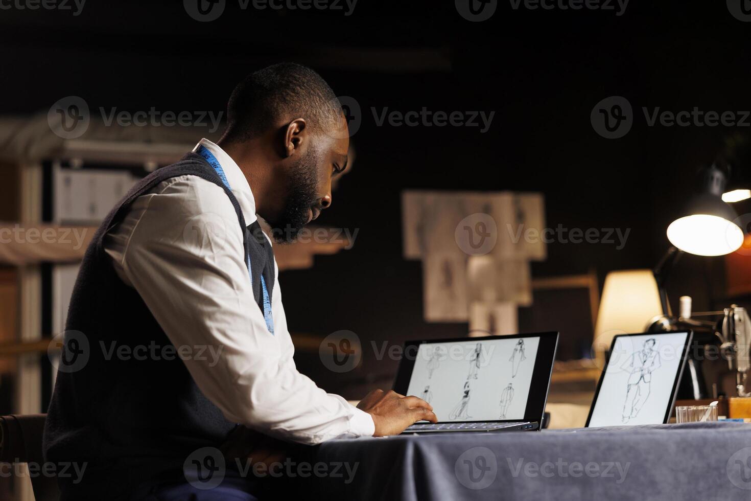 Dressmaker looking at creative fashionable outfit designs online for inspiration before drawing sartorial sketches on digital tablet. Fashion designer working on upcoming runway show collection photo