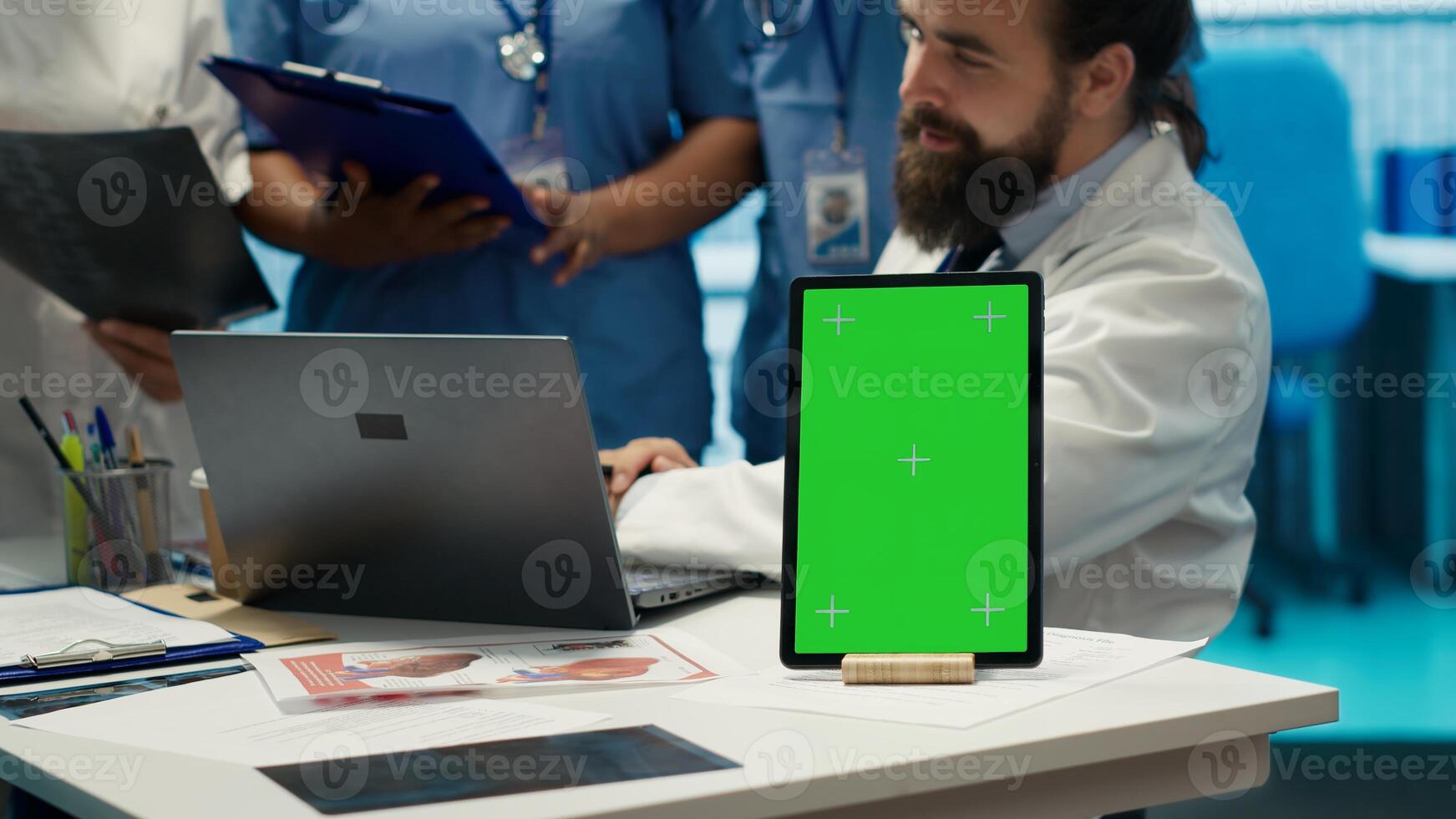 Doctors and nurses review radiography scans with green screen on desk, discuss potential diagnosis and treatment plans in private clinic. Professional experts staff work with expertise. Camera A. photo
