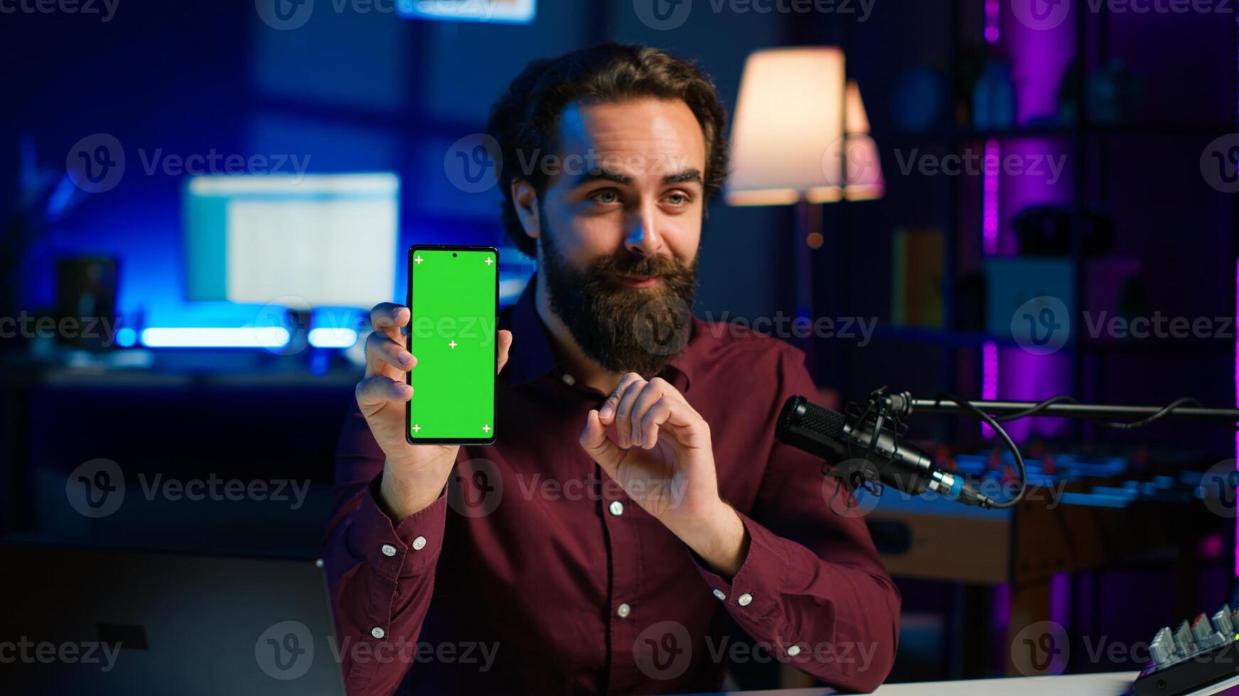 Upbeat tech specialist assessing mockup smartphone performance, feeling satisfied with high quality components used. Entertainer shooting isolated screen phone review for internet channel, camera A photo