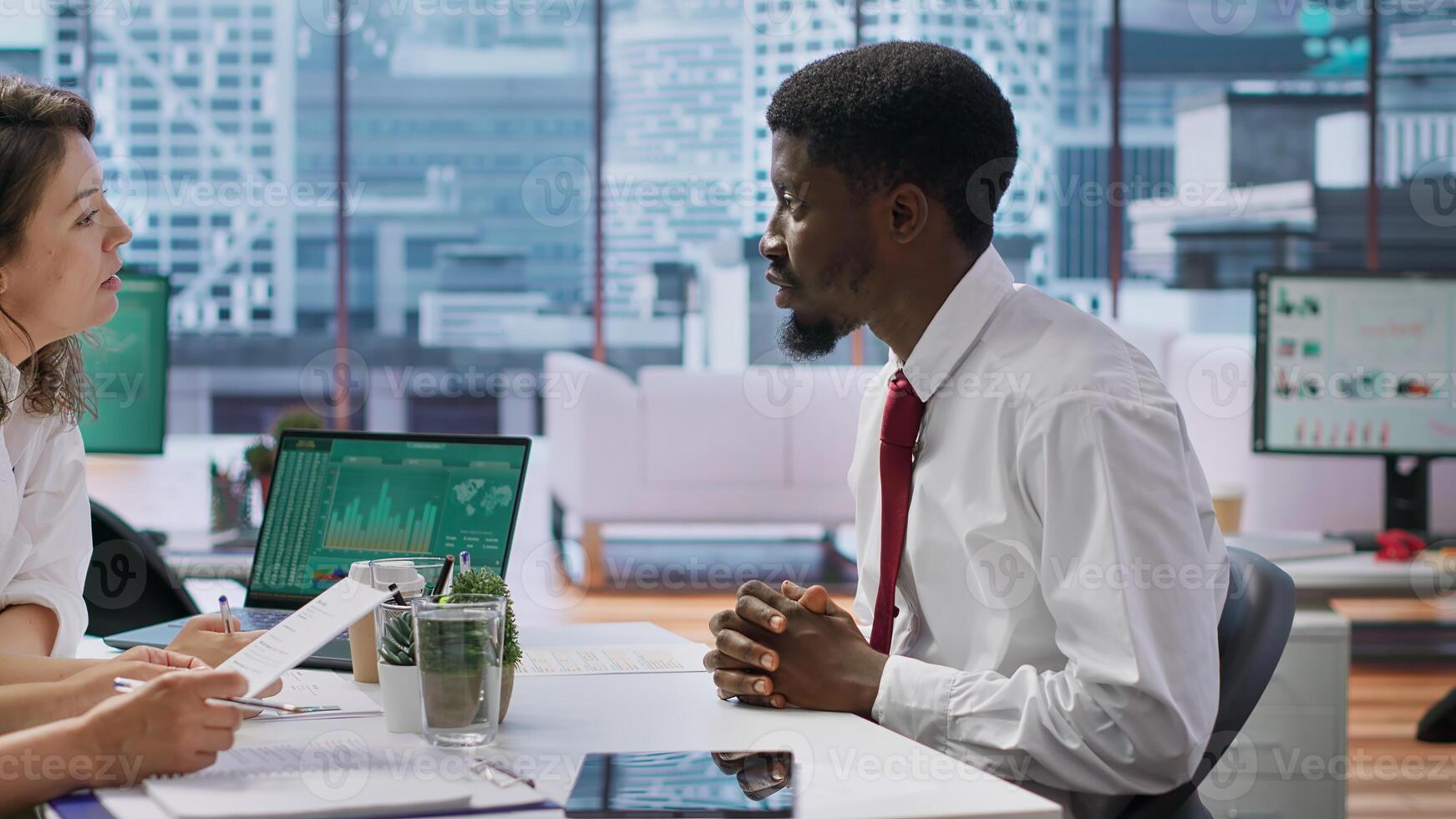Applicant gives his CV to human resources staff to begin the job interview, reviewing the qualifications and work experience from the application form. Discussing job roles available. Camera A. photo