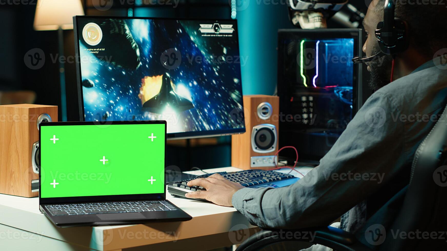 Isolated screen laptop next to professional streamer competing in online multiplayer videogame, streaming live at home. Mockup notebook and man playing on PC, using headphones to talk with audience photo