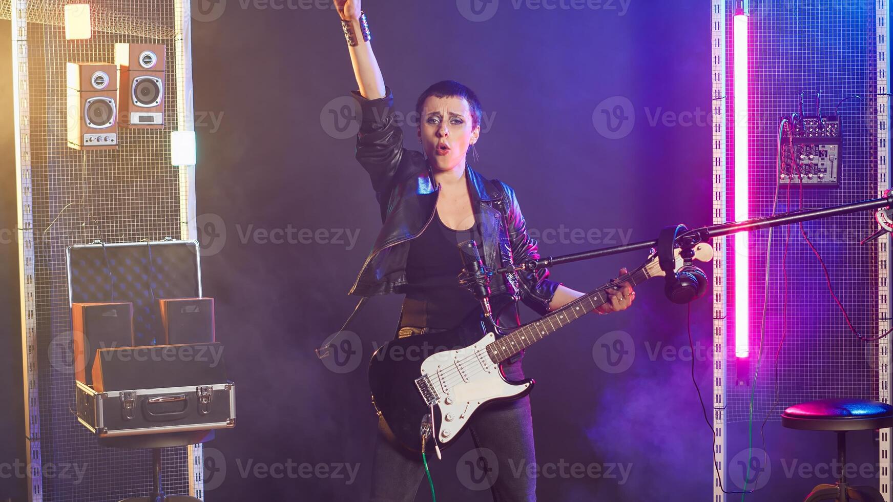 Punk rock girl with a grunge edgy style performing with a bass guitar in urban studio. Female rock star with bold attitude and fierce stage presence creating an iconic live performance. Camera B. photo