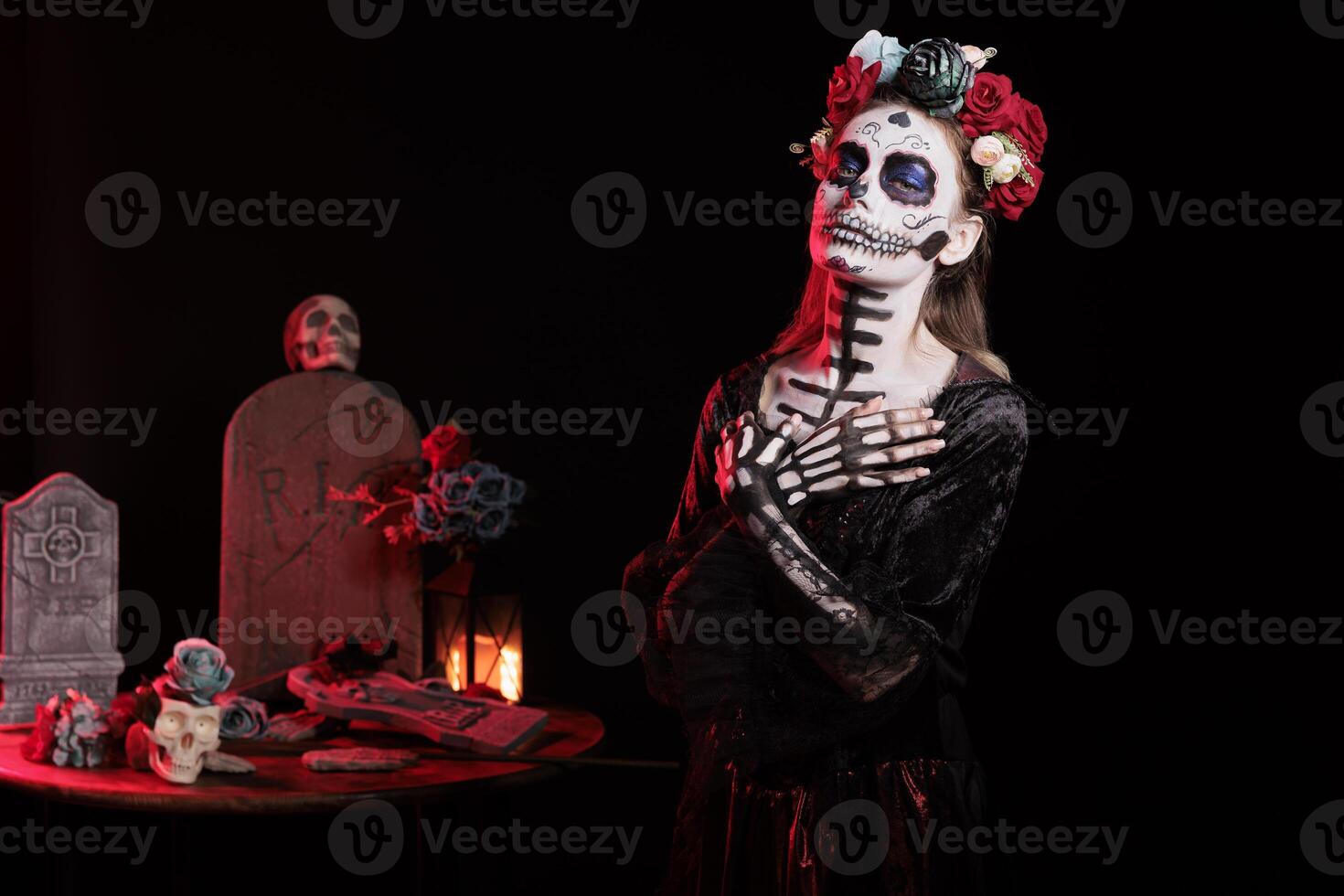 Woman dressed in Day of the Dead costume celebrating Dia de los Muertos, putting arms on chest. Lady wearing creepy skeleton corpse makeup promoting Mexican culture during Halloween photo