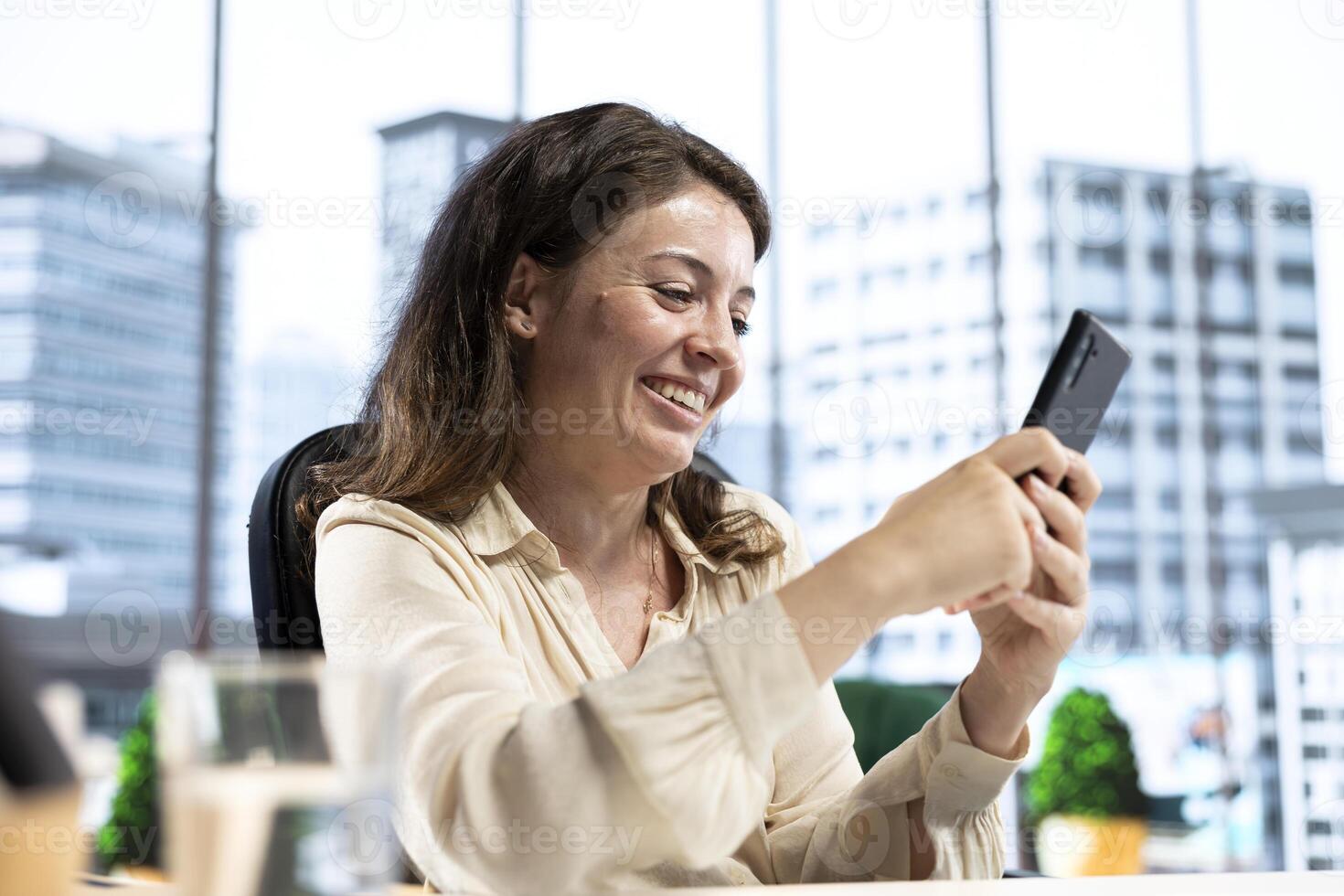 Pleased empowered businesswoman texting messages in her own director office, having fun on social media. Leader discussing with partners about new project ideas for career growth. photo