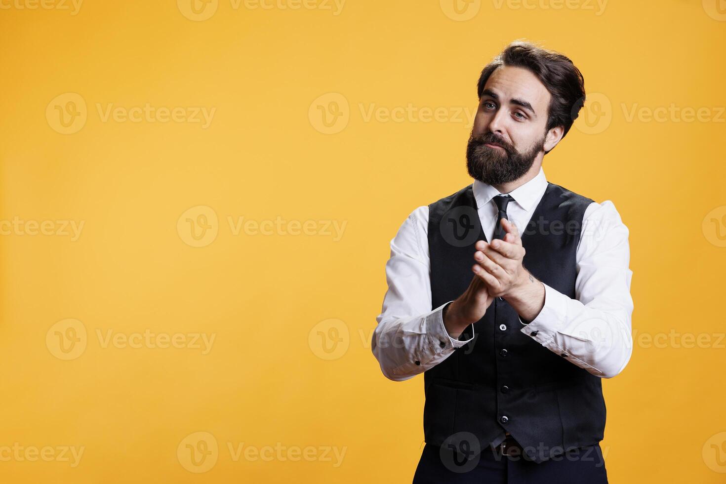 Friendly waiter clapping hands for person, trying to boost confidence and celebrate success in studio. Professional employee at restaurant applauding someone and presenting his congratulations. photo